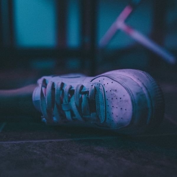 Athletic sneakers on a dark floor with blue light